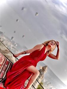 ギョレメにあるSevin Stone Hotelの手すりに立つ赤い服装の女