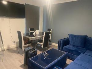 a living room with a blue couch and a table at MBA COSY 4 bedroom house in Leavesden Green