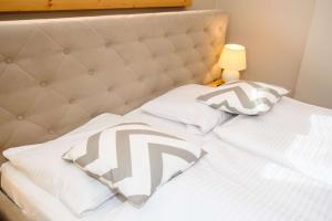 ein Bett mit weißer Bettwäsche und Kissen darauf in der Unterkunft Apartamenty Siuster z widokiem na góry - doskonała lokalizacja, niedaleko Term Bukovina in Bukowina Tatrzańska