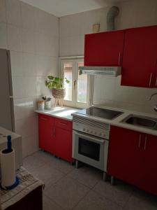 cocina con armarios rojos, fogones y fregadero en Apartamento ideal para familias, en Toledo