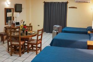ein Wohnzimmer mit einem Tisch, einem Bett und einem Sofa in der Unterkunft Hotel Las Fuentes in Los Mochis