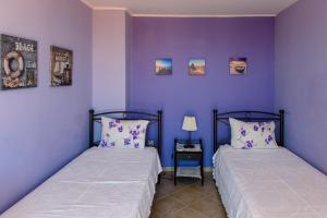 2 Betten in einem Zimmer mit lila Wänden in der Unterkunft Artemis Riviera in Artemida