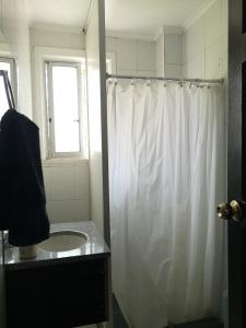 a bathroom with a white shower curtain and a sink at Hostal Vitalia in Santiago