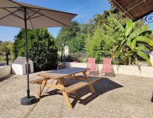 a picnic table and two chairs with an umbrella at L'Autre Maison 