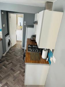 uma cozinha com armários brancos e um forno com placa de fogão em Wymington House em Bedford
