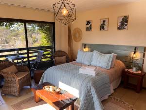een slaapkamer met een bed, een tafel en een raam bij Los Pecados de la Viuda in Punta Del Diablo +102 foto's