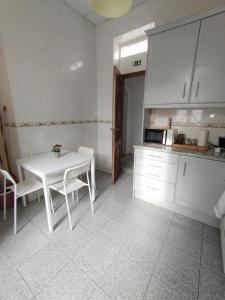 een keuken met een tafel en een witte tafel en stoelen bij The Tiles House in Faro