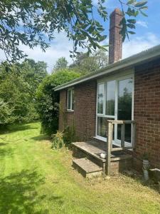 a brick house with a bench next to a window at Secluded 3 bed cottage in private parkland in Brockenhurst