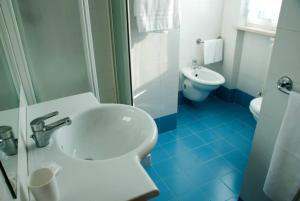 a blue and white bathroom with a sink and a toilet at Hotel Touring in Falconara Marittima
