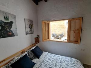 1 dormitorio con 1 cama y ventana con mesa en Apartamento La Zarzamora-Patio privado, en Jerez de la Frontera