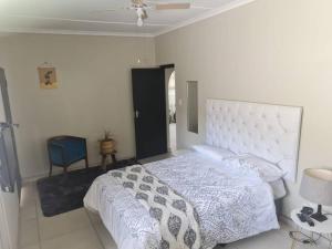 a bedroom with a white bed and a blue chair at Three Two in Richards Bay