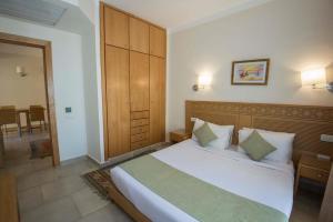 Eagles down town Zahabia &Beach Resort في الغردقة: غرفة نوم مع سرير أبيض كبير مع اللوح الأمامي الخشبي