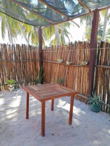 een houten picknicktafel voor een hek bij Casita Esmeralda in El Cuyo