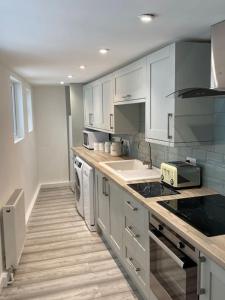 una cucina con mobili bianchi e un piano di lavoro di Lovely 1 bed flat 200 metres from beach a Walton-on-the-Naze Altre 37 foto