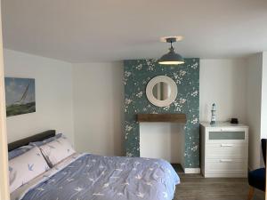 una camera da letto con un letto e uno specchio a parete di Lovely 1 bed flat 200 metres from beach a Walton-on-the-Naze
