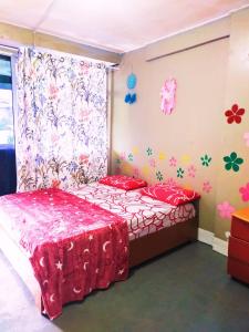 a bedroom with a bed with red sheets and flowers on the wall at Dreamcatcher Homestay, Kundasang in Ranau