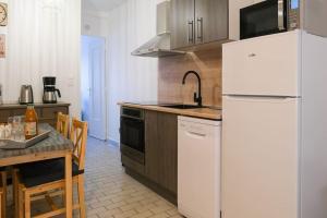 a kitchen with a white refrigerator and a table at Les Chevalets IV in Lens +14 photos