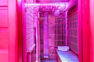 un couloir avec des lumières roses et un banc dans une chambre dans l'établissement GlamappartSpa design luxe & Parking, à Dijon