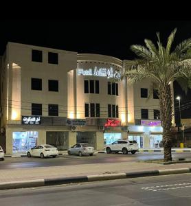un edificio con coches estacionados en un estacionamiento por la noche en فندق المنصور, en Aḑ Ḑabbīyāt al Janūbīyāt
