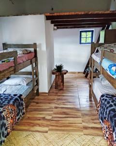 a room with three bunk beds and a wooden floor at Espaço Cultural Lotus - Suítes, Hostel e Camping in Alto Paraíso de Goiás