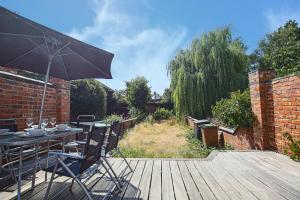 a table and chairs with an umbrella on a wooden deck at Thrift House - Central Location - Free Parking, Pool Table, Fast Wifi, Smart TV with Fast Wifi by Yoko Property in Northampton