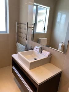ein Badezimmer mit einem weißen Waschbecken und einem Spiegel in der Unterkunft Sweet home in Albany in Auckland