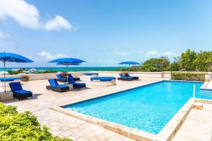 a swimming pool with blue chairs and umbrellas at Sea Esta Studio I - Ideal for Couples! in Turtle Cove