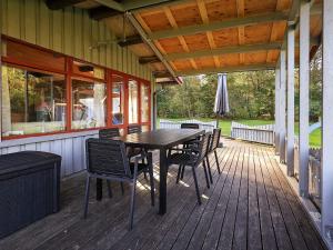 una terraza de madera con mesa y sillas en una casa en Four-Bedroom Holiday home in Roslev 3, en Nøreng