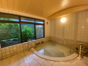 a large tub in a bathroom with a window at Gora Onsen Kinkaku 金閣莊 預約制免費個人湯屋 Private onsen free by Reservation in Hakone