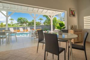 un salon avec une table et des chaises et une piscine dans l'établissement Villa Green Caraibes, à Saint-François