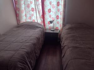 two beds in a small room with a window at Apart Hotel Curicó in Curicó