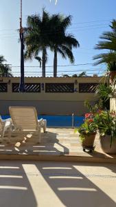 uma cadeira branca sentada num pátio com plantas em casa 300 mts da praia em Juquei