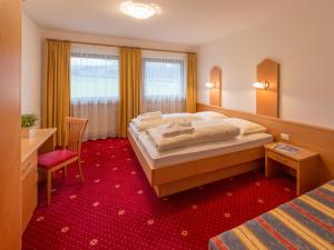 ヴァルダーオラにあるAppartements Steinerの赤いカーペットフロアのベッドルーム1室(大型ベッド1台付)