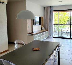 eine Küche mit einem Tisch und Stühlen sowie einem TV in der Unterkunft Iloa 3 quartos Luxo in Barra de São Miguel
