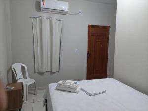 a room with a bed with a white table and a chair at Pousada BG Lençóis in Barreirinhas