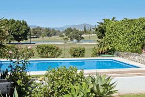 una piscina en un jardín con un campo de golf en Cortijada de Marta, en Fuengirola