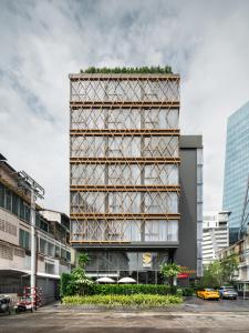 曼谷的住宿－Seekers Finders Rama IV Hotel SureStay Collection by BW，一座高大的建筑,旁边是植物