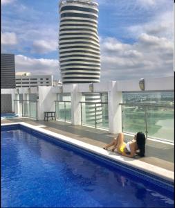 a woman laying on the edge of a swimming pool at Ecusuites Super Host Penthouse 10 River View Puerto Santana in Guayaquil
