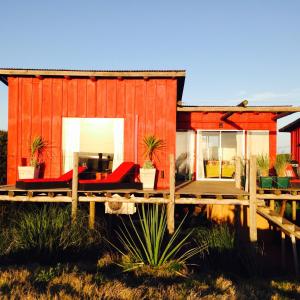 una casa roja con una terraza de madera delante de ella en BDL Beach Design loft Two, en José Ignacio