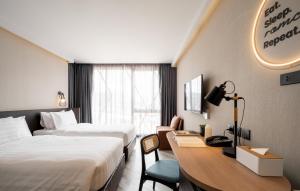 a hotel room with two beds and a desk at Seekers Finders Rama IV Hotel SureStay Collection by BW in Bangkok