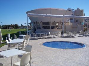 a patio with tables and chairs next to a pool at Bowker Apartment in Protaras