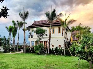 a house with palm trees in front of it at Rice Villa Chiang Mai in Ban Wang Mun