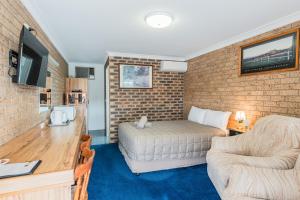 a room with a bed and a couch and a desk at Settlers Motor Inn in Tenterfield