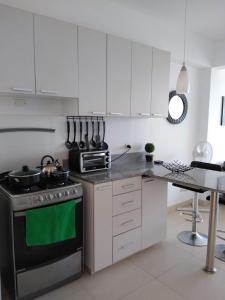 a kitchen with white cabinets and a stove top oven at Acogedor departamento WiFi in Piura