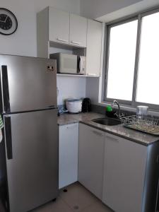 a kitchen with a refrigerator and a sink at Acogedor departamento WiFi in Piura