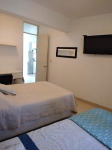 a bedroom with two beds and a refrigerator at Acogedor departamento WiFi in Piura