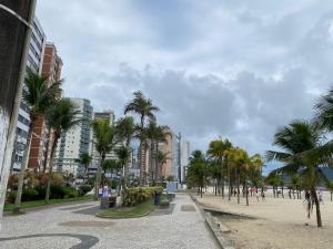 uma rua da cidade com palmeiras e edifícios em Kit Jd Guilhermina na Praia Grande