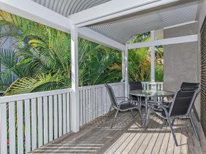 a porch with a table and chairs and palm trees at 8 Riverbreeze in Noosaville