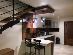 una cocina con una escalera con 2 sillas y una barra en Quinta Hotel los Duraznos, en Villa Doctor Mora