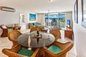 a dining room with a glass table and wicker chairs at Lagoon Beachfront Lodge 107 on Hamilton Island by HamoRent in Hamilton Island